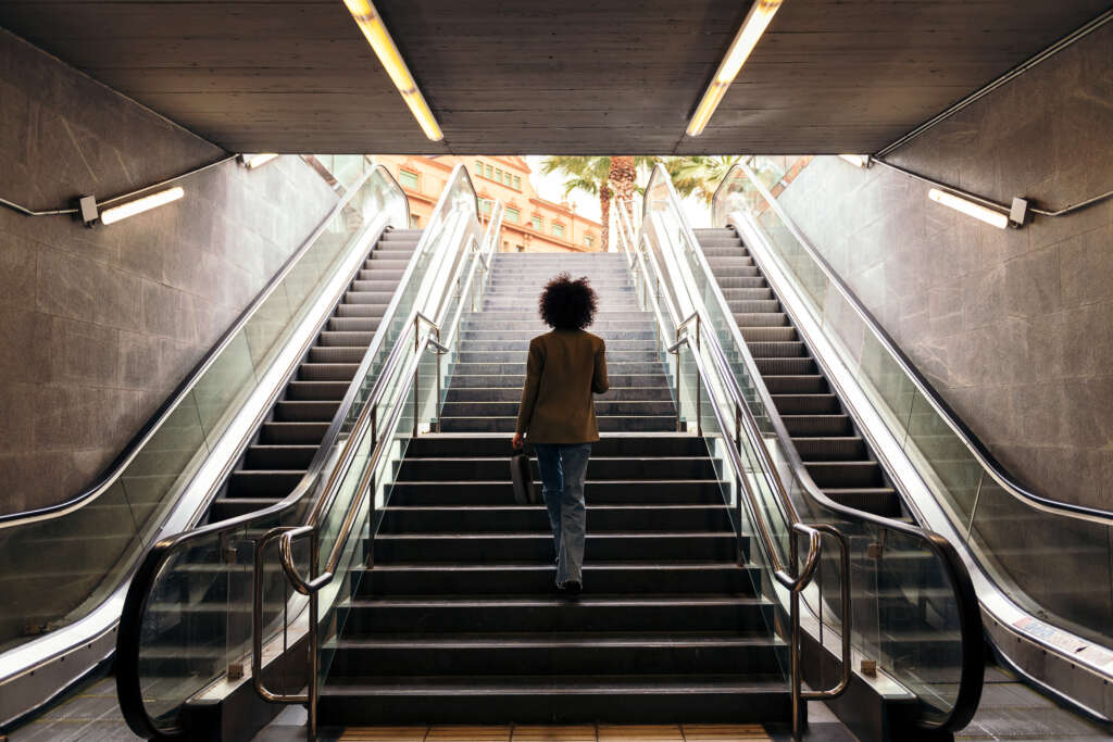 rear view of the silhouette of an unrecognizable business woman walking up the stairs of the subway station with a briefcase in her hand, concept of urban lifestyle and growth Part of an article on stealing fitness, taking small steps in everyday life to get fit without a large impact.