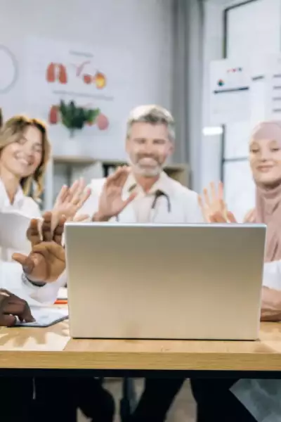 group of physiotherapists around a laptop conducting online treatments