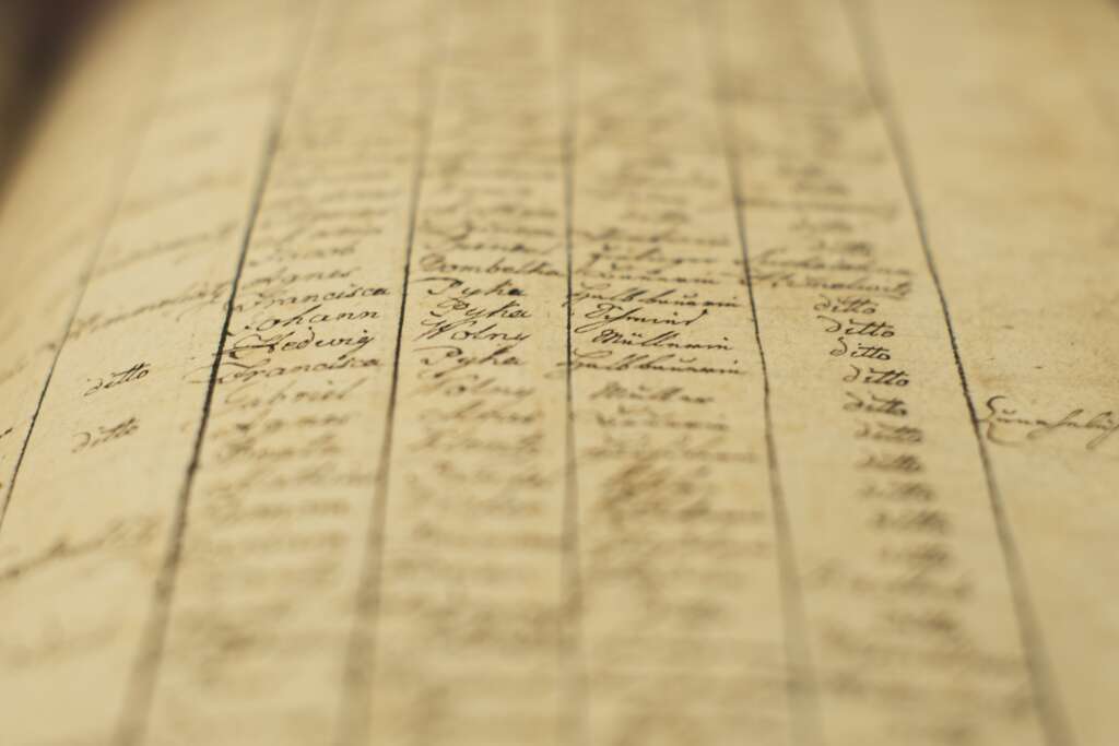 A soft focus of an old book of local records with list of residents names and information. relating to NHS Waiting lists