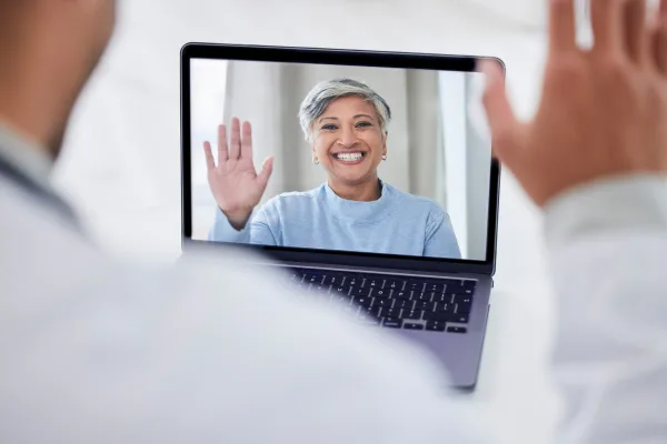 Video based online physiotherapy appointment physio and patient are waving